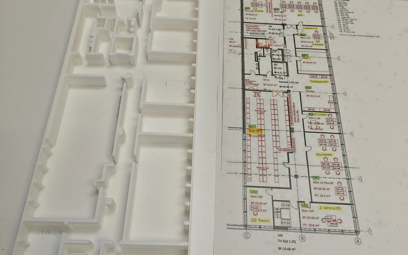 Gedrucktes Grundriss-Relief neben dem Bauplan, aus dem es entstanden ist